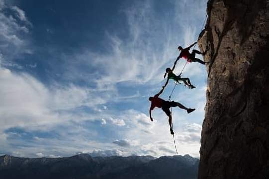 mountain climbers rappelling in a row